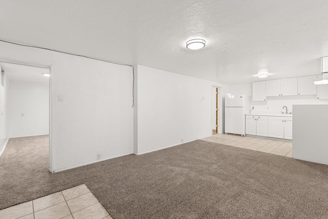 unfurnished living room with a textured ceiling, light colored carpet, and sink