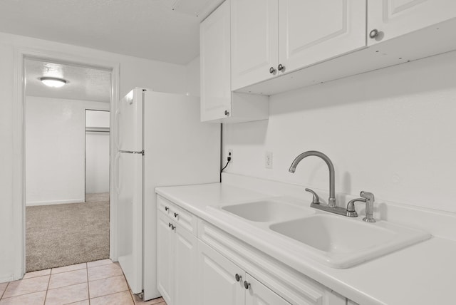 kitchen with a textured ceiling, light colored carpet, sink, white refrigerator, and white cabinets