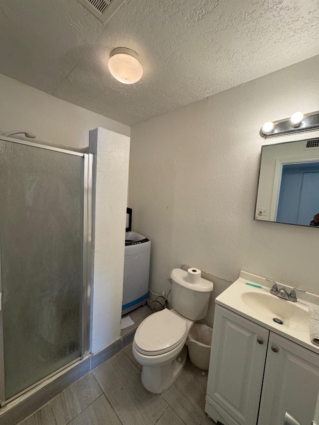 full bath featuring vanity, a shower stall, toilet, and a textured ceiling