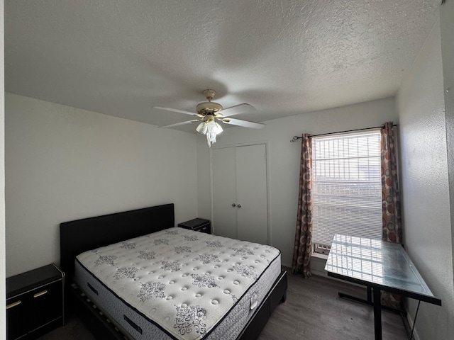 bedroom featuring a closet, dark wood finished floors, a textured ceiling, and ceiling fan