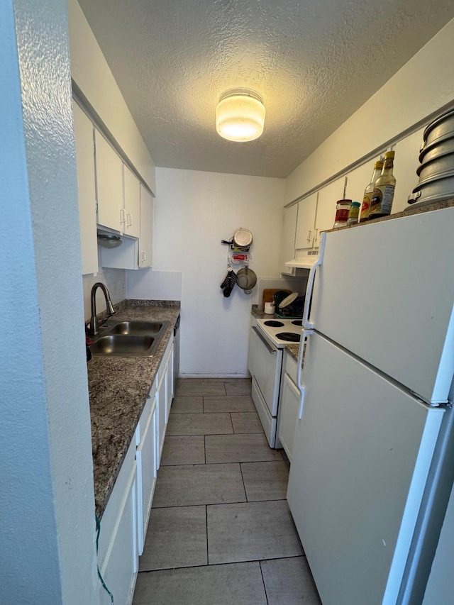 kitchen featuring dark countertops, under cabinet range hood, white cabinets, white appliances, and a sink