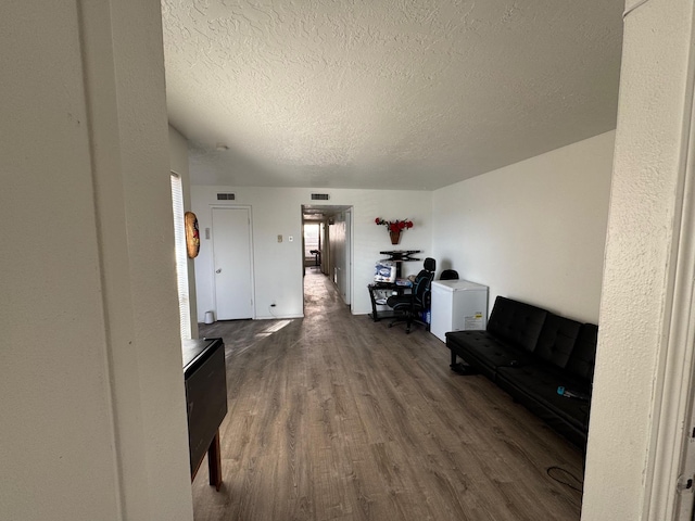 living area with wood finished floors, visible vents, and a textured ceiling