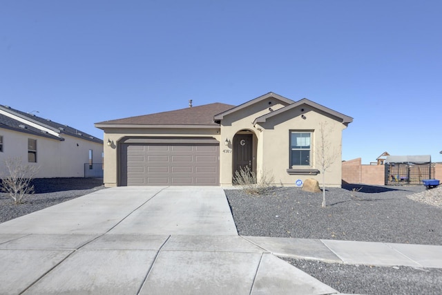 view of front of house with driveway, an attached garage, fence, and stucco siding