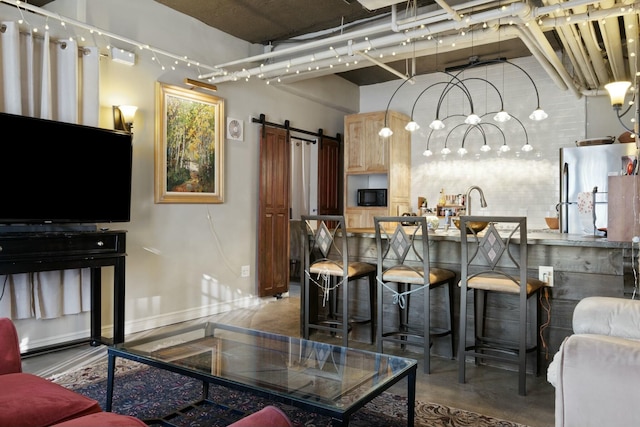 living room featuring a barn door, concrete flooring, and sink