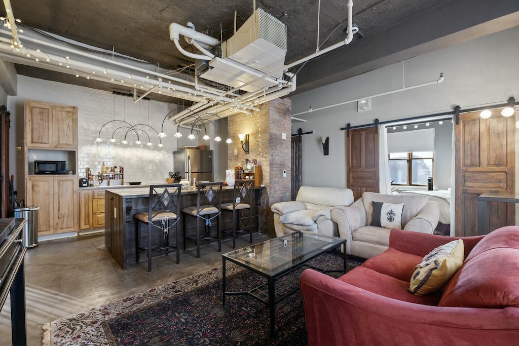 living room with a barn door, a towering ceiling, and brick wall