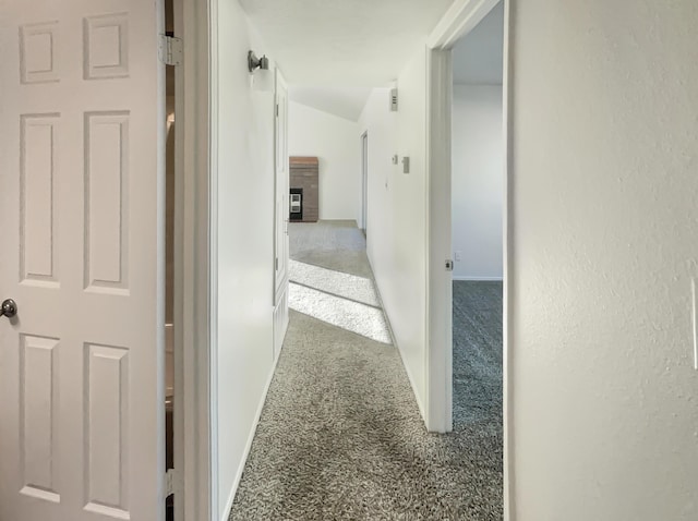 hallway with carpet flooring and vaulted ceiling