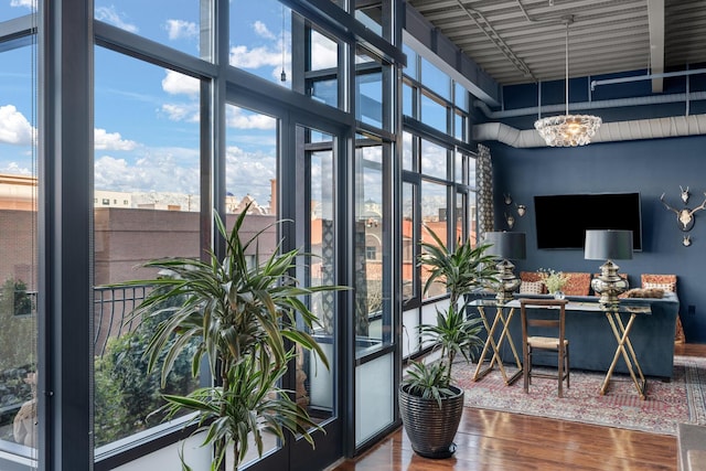 office space with an inviting chandelier, a towering ceiling, wood-type flooring, and expansive windows