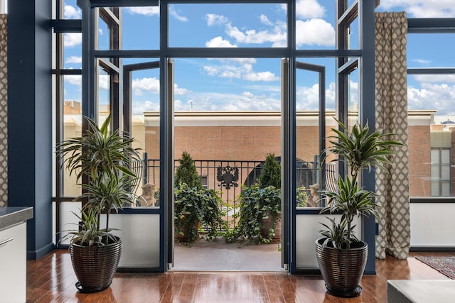 doorway to outside featuring a healthy amount of sunlight, a wall of windows, and wood-type flooring