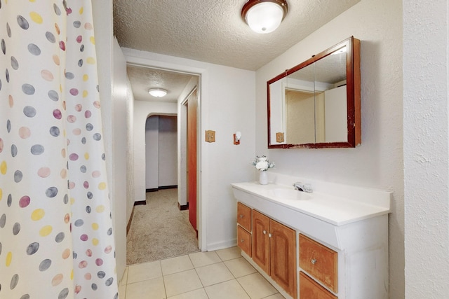 bathroom featuring tile patterned flooring, vanity, a textured ceiling, and walk in shower