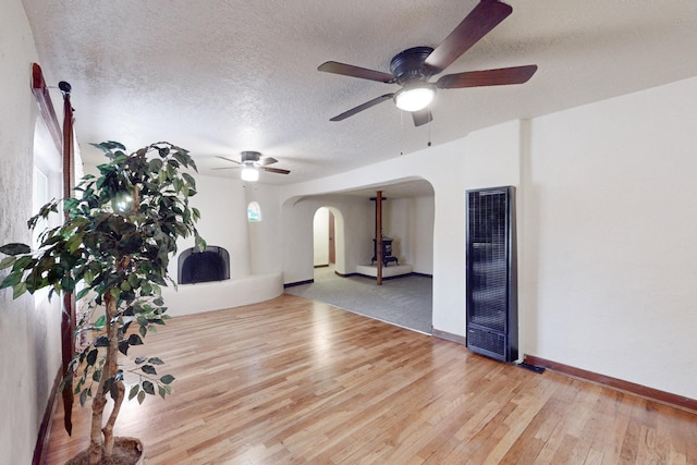 interior space with ceiling fan, a textured ceiling, and light wood-type flooring