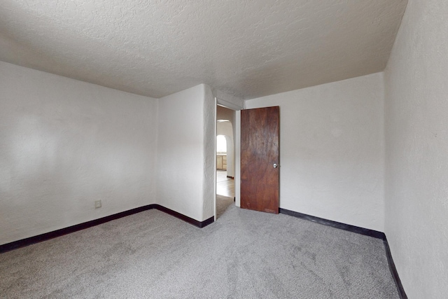 empty room with a textured ceiling and light carpet