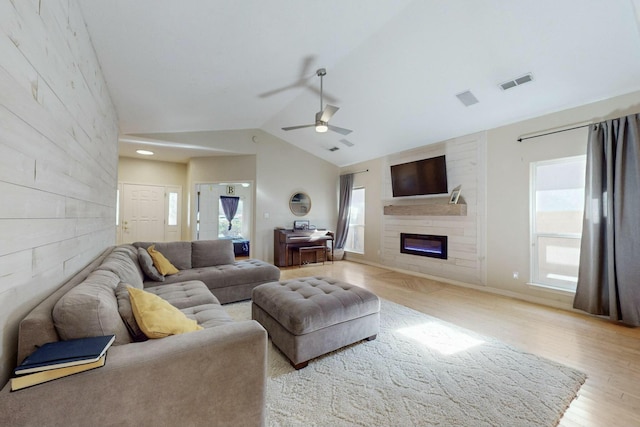 living room with a large fireplace, light hardwood / wood-style flooring, ceiling fan, and lofted ceiling