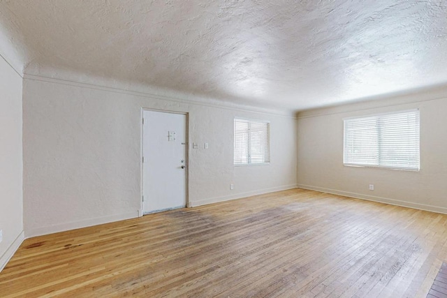 spare room with light hardwood / wood-style flooring and a textured ceiling