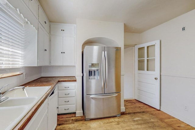 kitchen featuring stainless steel fridge, light wood-type flooring, white cabinetry, and sink