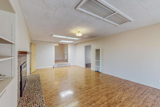 living room with built in shelves, a fireplace, and light hardwood / wood-style floors