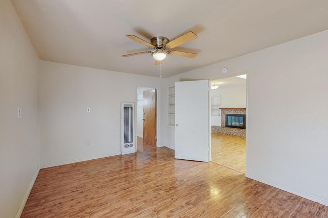 unfurnished room featuring ceiling fan, built in shelves, and light hardwood / wood-style flooring