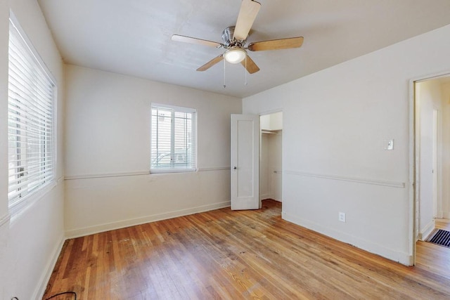 unfurnished bedroom featuring ceiling fan, a closet, a walk in closet, and light hardwood / wood-style flooring