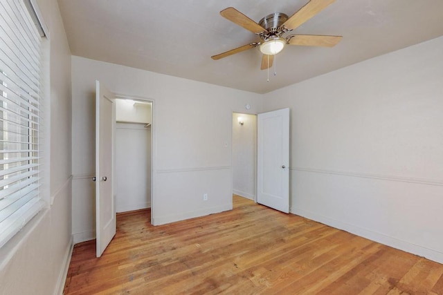 unfurnished bedroom featuring ceiling fan, a closet, a walk in closet, and light hardwood / wood-style flooring