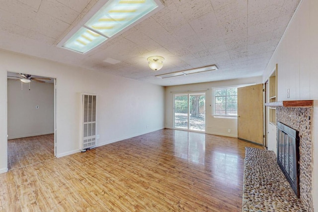 unfurnished living room featuring a fireplace, light hardwood / wood-style floors, and ceiling fan