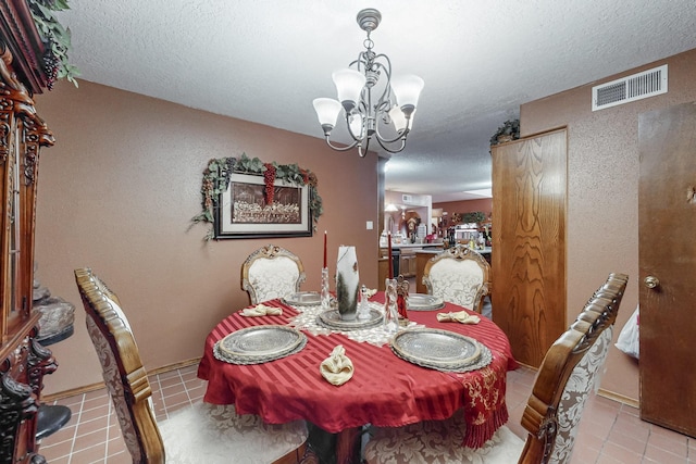 dining area featuring light tile patterned floors, a textured ceiling, and an inviting chandelier