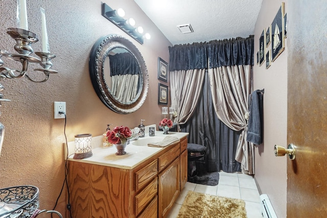 bathroom featuring tile patterned flooring, vanity, a textured ceiling, and a baseboard heating unit