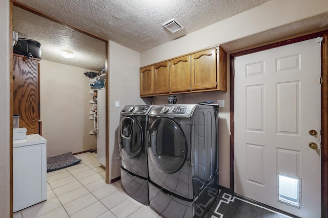 laundry area with cabinets, separate washer and dryer, a textured ceiling, and light tile patterned floors