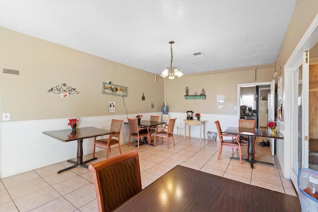 dining space with light tile patterned floors, a textured ceiling, and an inviting chandelier