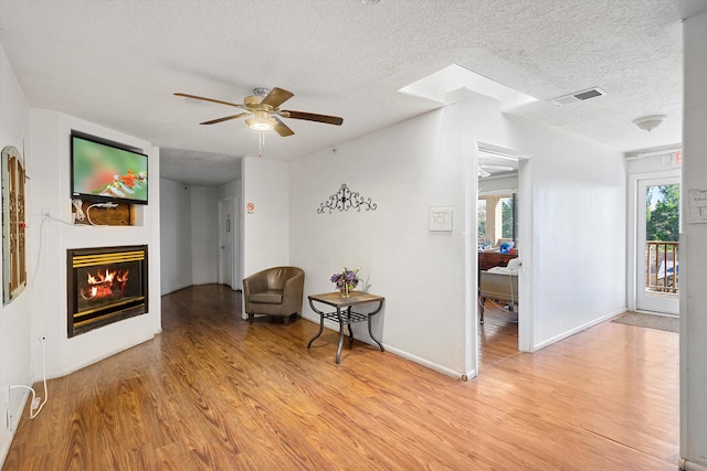 sitting room with ceiling fan, light hardwood / wood-style floors, and a textured ceiling