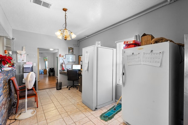 kitchen featuring white refrigerator, light tile patterned flooring, a textured ceiling, and an inviting chandelier