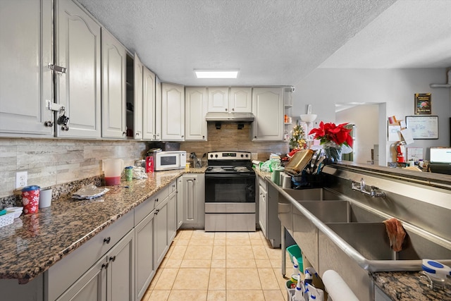 kitchen featuring a textured ceiling, backsplash, light tile patterned floors, and stainless steel range with electric cooktop