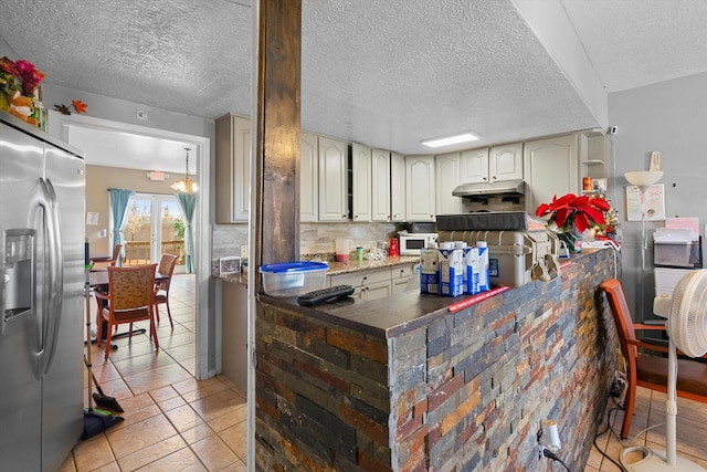 kitchen with backsplash, stainless steel fridge with ice dispenser, light tile patterned floors, and a textured ceiling