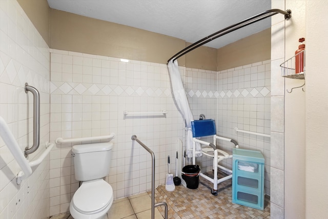 bathroom with a shower with curtain, tile patterned flooring, a textured ceiling, toilet, and tile walls