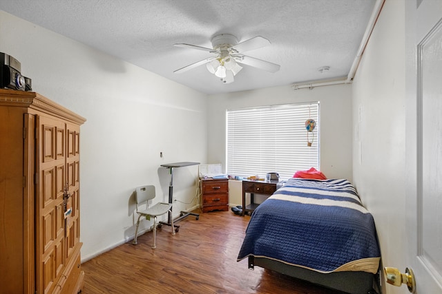 bedroom with ceiling fan, hardwood / wood-style floors, and a textured ceiling