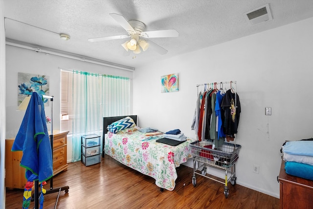 bedroom with ceiling fan, dark hardwood / wood-style flooring, and a textured ceiling