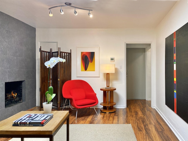 living room featuring dark wood-type flooring and a tiled fireplace