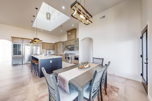 dining room with a high ceiling, an inviting chandelier, and sink