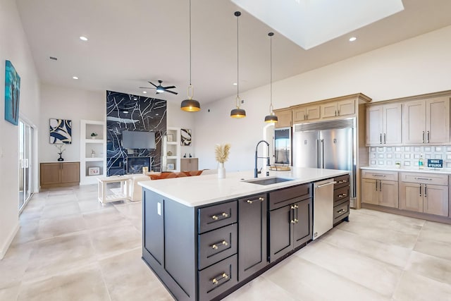 kitchen with built in shelves, ceiling fan, sink, decorative light fixtures, and an island with sink