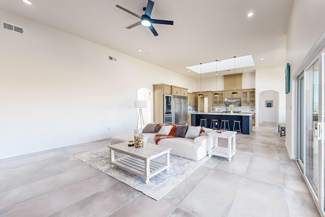 living room featuring ceiling fan, sink, and a high ceiling