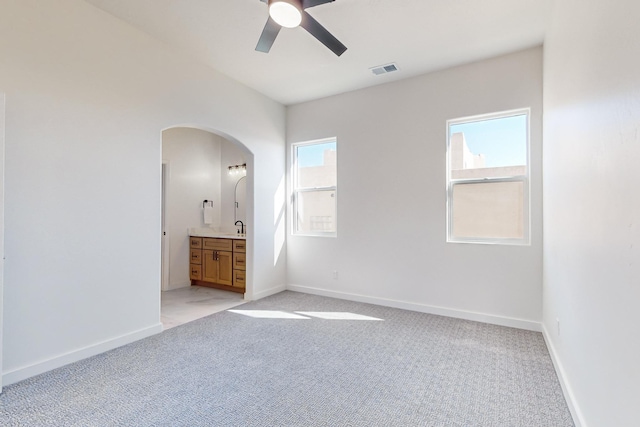 unfurnished bedroom featuring ceiling fan, sink, light carpet, and connected bathroom