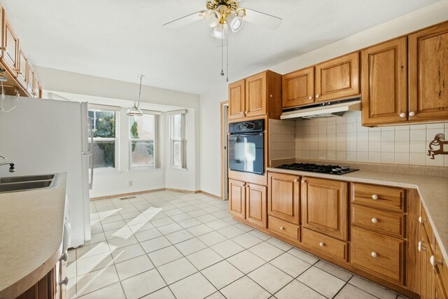 kitchen with pendant lighting, sink, backsplash, black appliances, and light tile patterned flooring