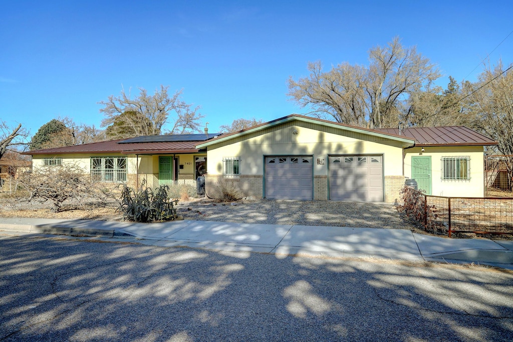 single story home with solar panels and a garage