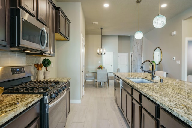 kitchen with sink, decorative light fixtures, decorative backsplash, appliances with stainless steel finishes, and dark brown cabinets