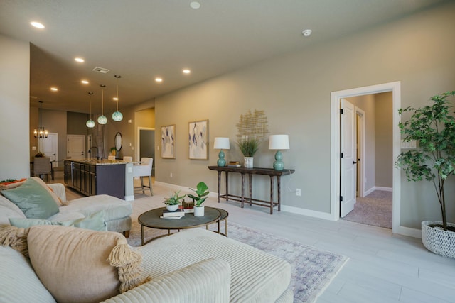 living room with light hardwood / wood-style flooring, sink, and a chandelier