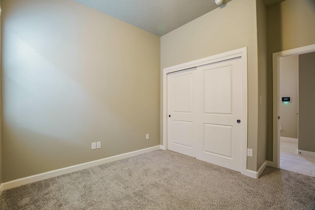 unfurnished bedroom with light carpet, a closet, and a textured ceiling