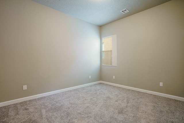 empty room with carpet floors and a textured ceiling