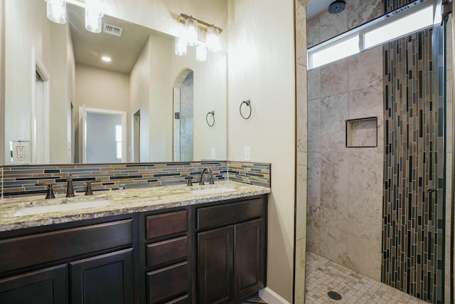 bathroom featuring a tile shower, vanity, and tasteful backsplash