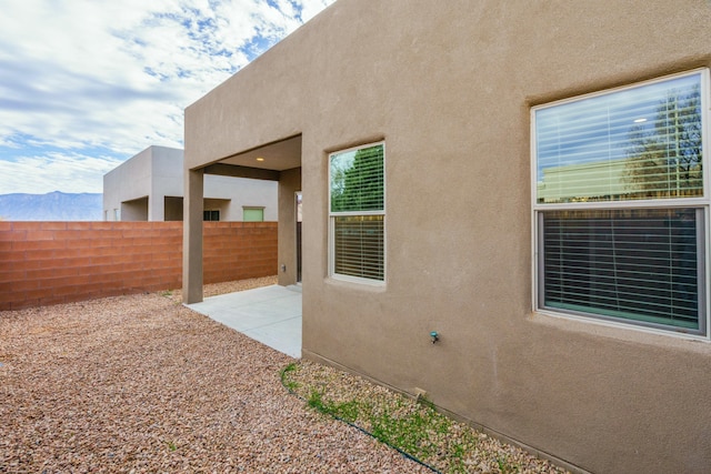 view of property exterior with a mountain view and a patio