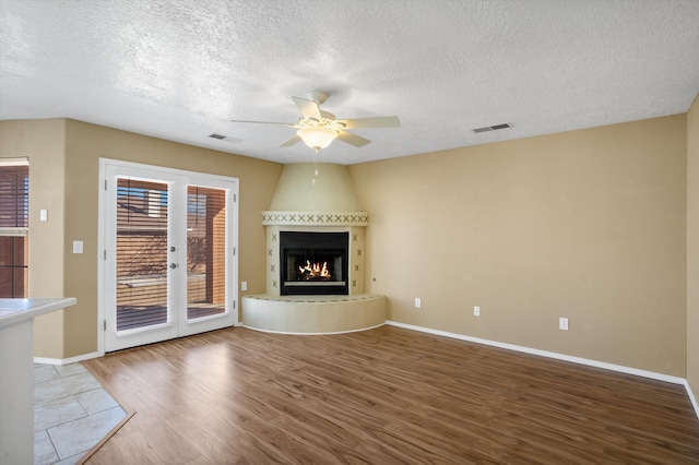 unfurnished living room featuring a fireplace, a textured ceiling, hardwood / wood-style flooring, and ceiling fan