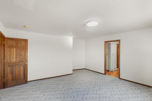 carpeted spare room with a baseboard radiator