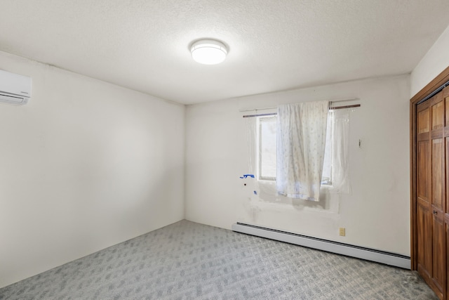 carpeted spare room with a textured ceiling, a wall unit AC, and a baseboard heating unit